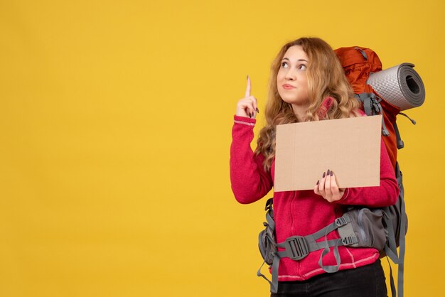 Young travelling girl collecting her luggage showing free space for writing and pointing up