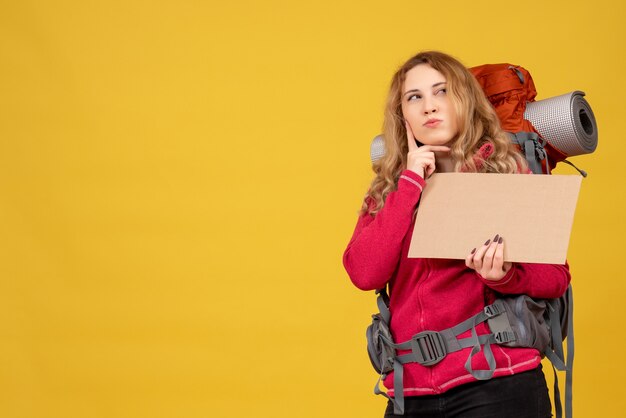 Молодая путешествующая девушка собирает свой багаж, показывая свободное место для письма, глубоко размышляя