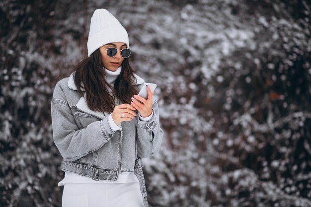 Young trendy girl in a winter park using phone