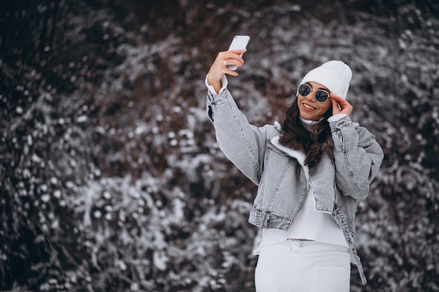 Young trendy girl in a winter park using phone