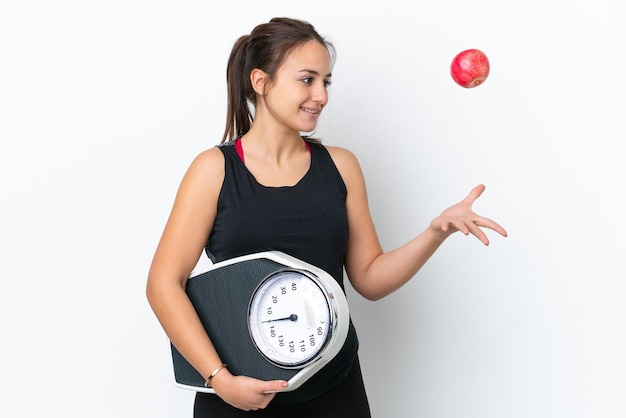 Young ukrainian woman isolated on white background with weighing machine and with an apple