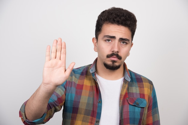 Free photo young unhappy man holding his hand up and upset something he did.