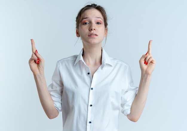 Young upset blonde russian girl points up isolated on white space with copy space