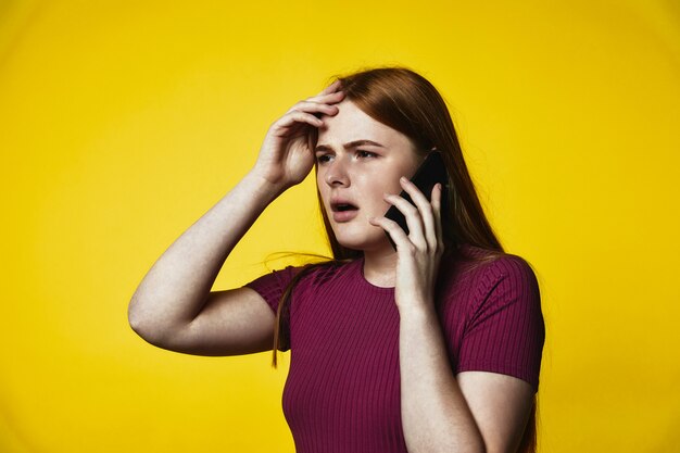 young upset redhead caucasian girl is talking on the cellphone