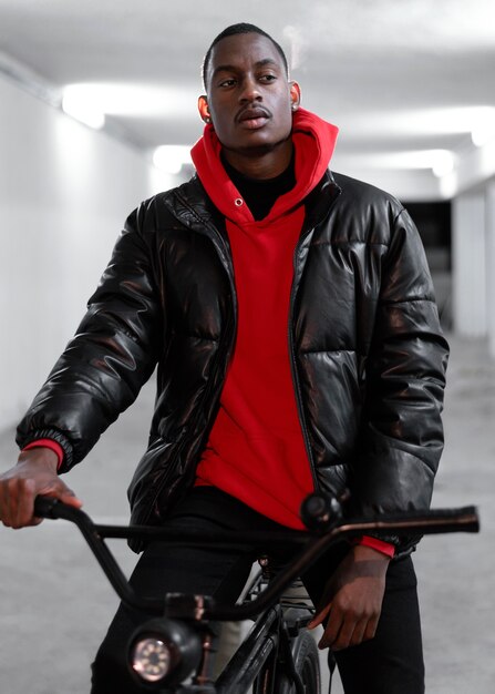 young urban man walking with his bike