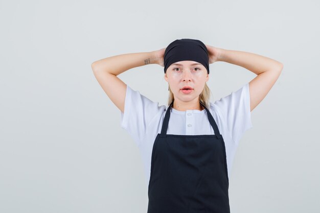 制服とエプロンで頭の後ろに手を握って若いウェイトレス