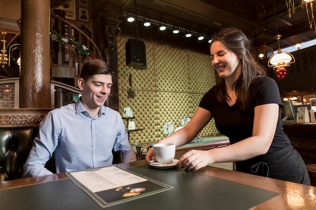 Young waitress serving coffee to customer