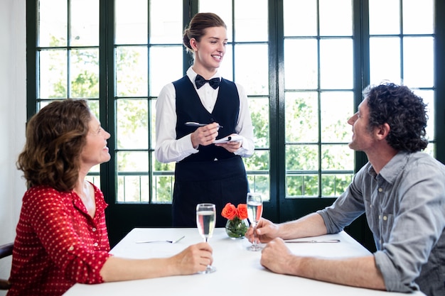 Молодая официантка принимает заказ от пары