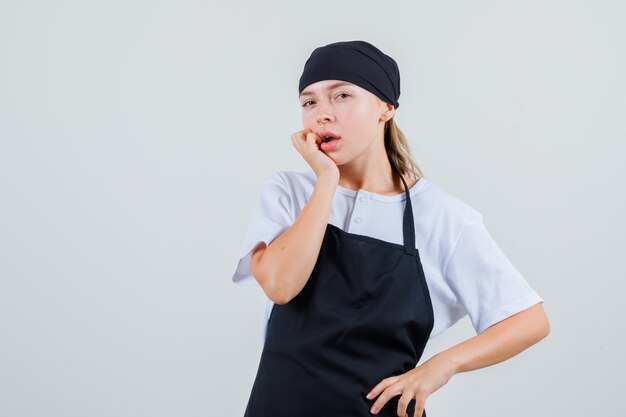 制服とエプロンの若いウェイトレスが見ていると思慮深く見える