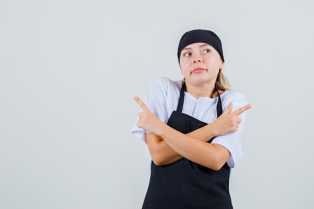 Young waitress in uniform and apron pointing to side