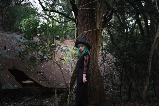 Young witch in dark forest