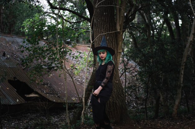 Young witch near tree trunk