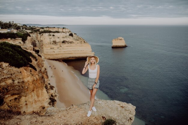 Young woman admiring breathtaking view while standing on very edge of mountain top