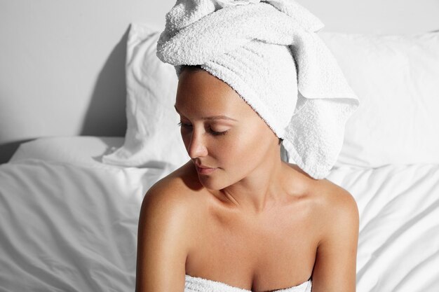 Young woman after bath sitting on a bed