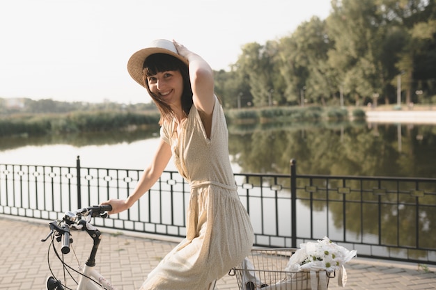 Free photo young woman against nature background with bike