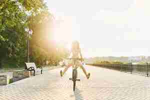 Free photo young woman against nature background with bike