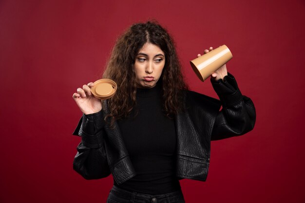 Young woman in all black outfit with opened empty cup.