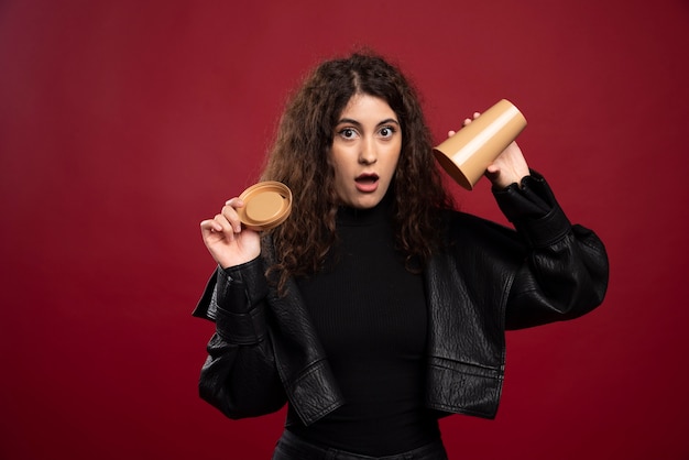 Young woman in all black outfit with opened empty cup.