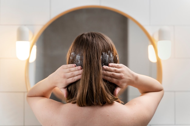 Young woman applying anti dandruff product