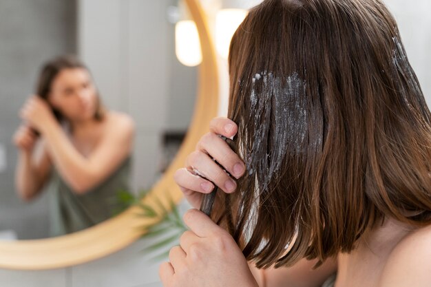 Young woman applying anti dandruff product