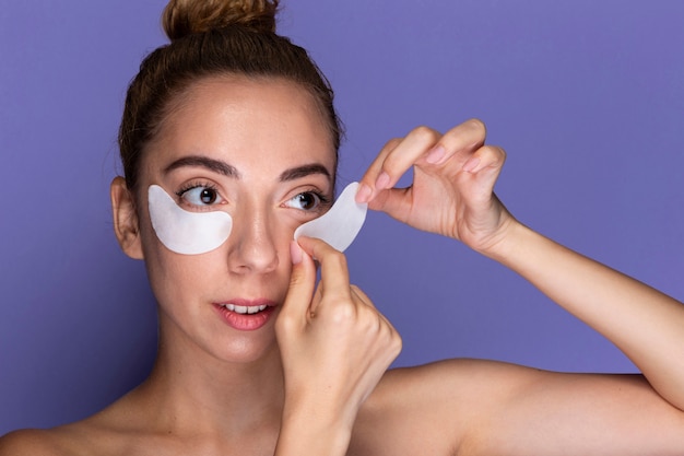 Young woman applying eye pads