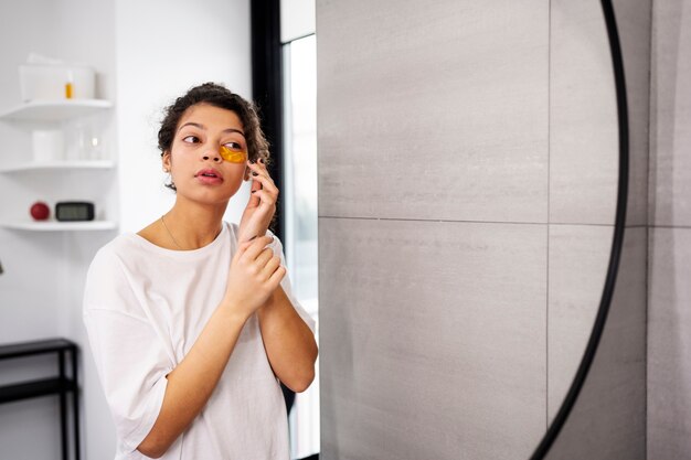 Young woman applying eye patch medium shot