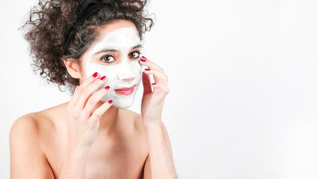 흰색 배경에 얼굴 화장품 마스크를 적용하는 젊은 여자