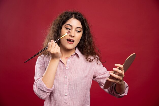 Young woman applying her makeup with brush.