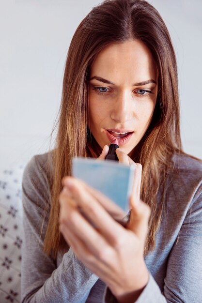 Young woman applying lipstick