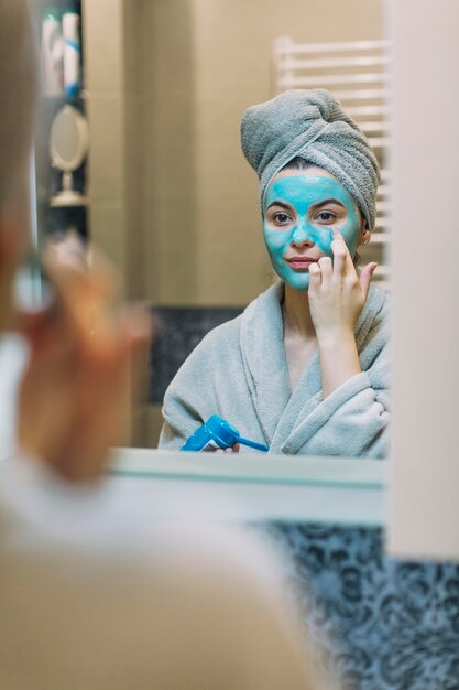 Young woman applying mask on face
