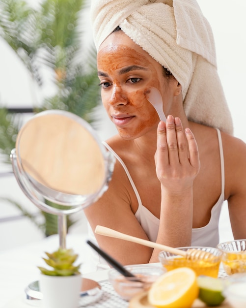 Free photo young woman applying a natural face mask