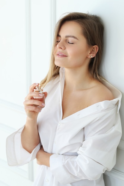 Free photo young woman applying perfume.