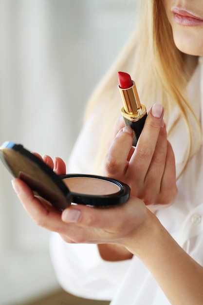 Free photo young woman applying red lipstick.