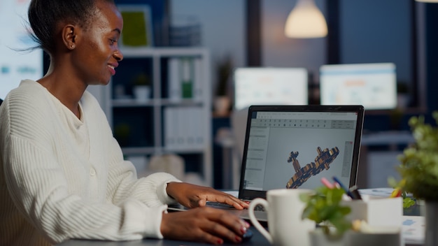 Young woman architect working in modern cad program overtime sitting at desk in start-up business office