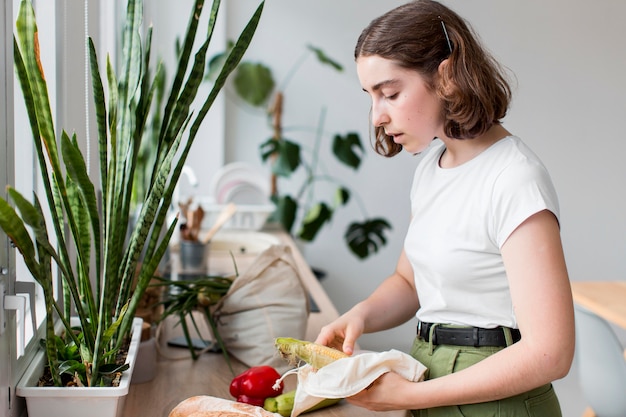 若い女性が台所で有機野菜をアレンジ