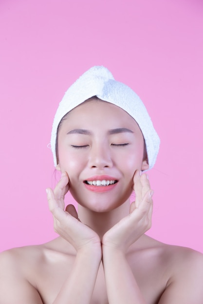 Молодая женщина Азии с чистой свежей кожей касается собственного лица, выразительных выражений лица, косметологии и спа.
