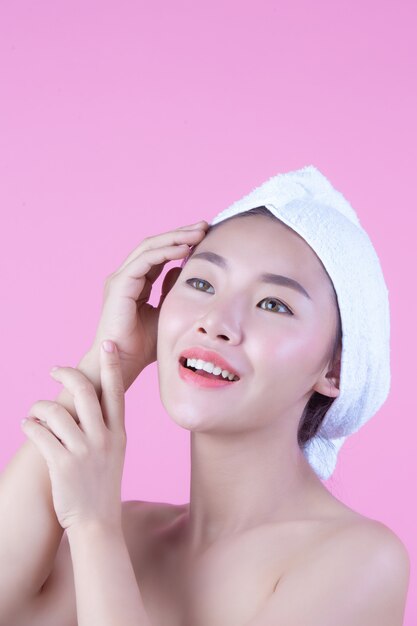 Молодая женщина Азии с чистой свежей кожей касается собственного лица, выразительных выражений лица, косметологии и спа.