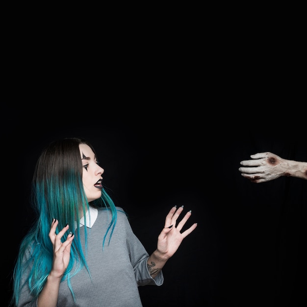 Free photo young woman astonished by zombie arm