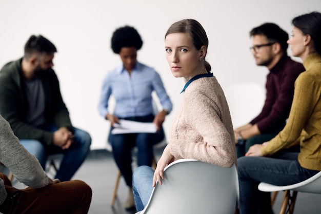 Young woman attending group therapy and looking at camera