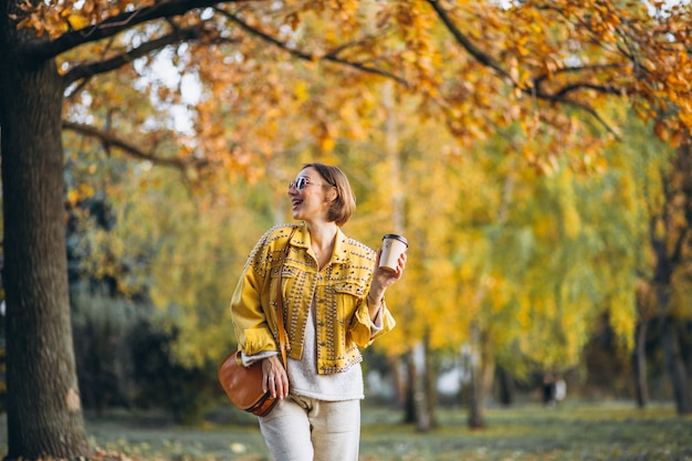 Young woman in an autumn park drinking coffee