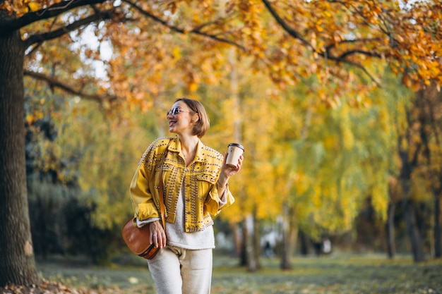 Young woman in an autumn park drinking coffee