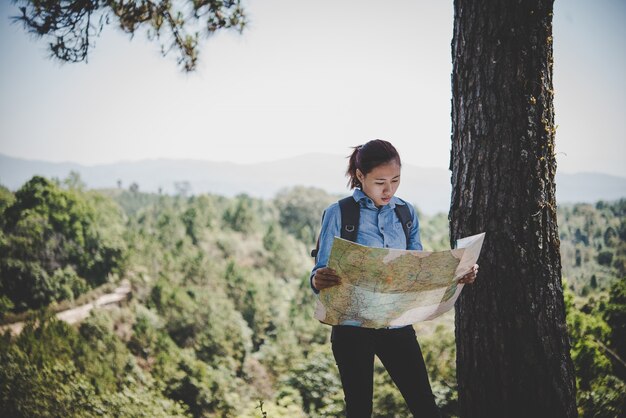 Young woman backpacker hiker reading map hiking trip. Relaxing on holiday.