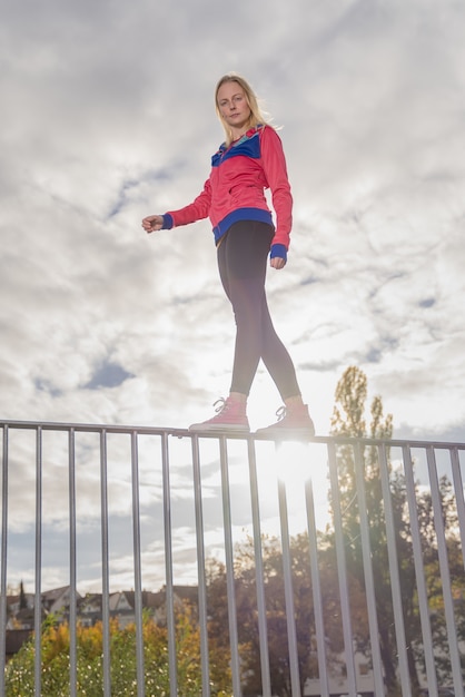 Free photo young woman balancing on a handrail