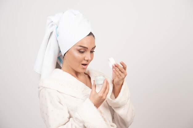 Young woman in a bathrobe applying a cream .