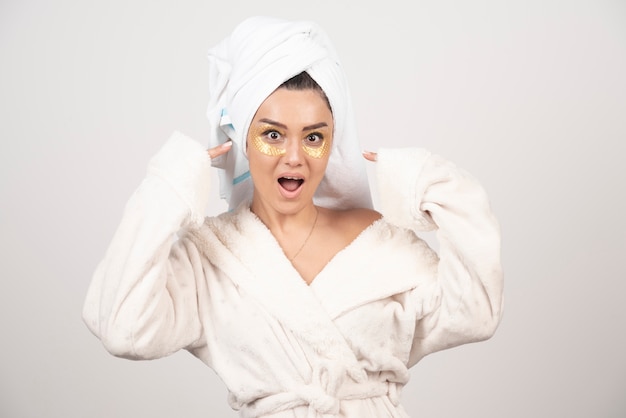 Young woman in bathrobe and cosmetic eye patches posing