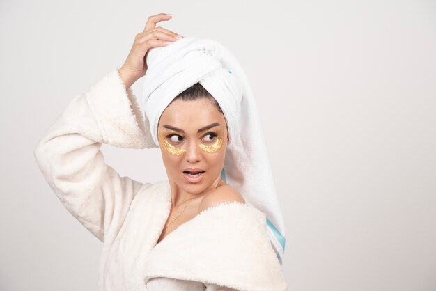 Young woman in bathrobe and cosmetic eye patches posing