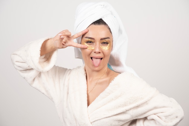 Young woman in bathrobe and cosmetic eye patches posing