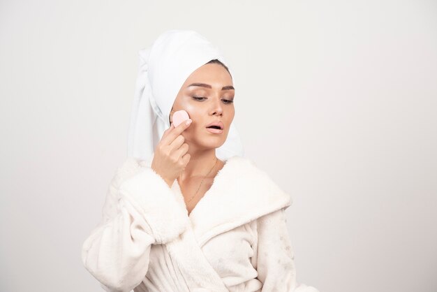 Young woman in a bathrobe doing make-up