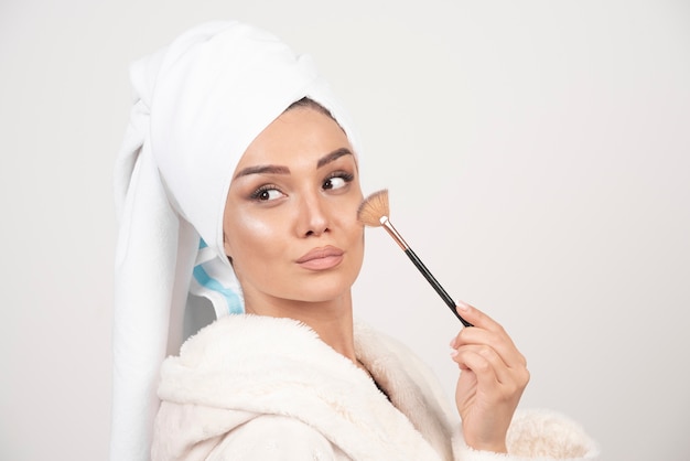 Young woman in a bathrobe holding make-up brush