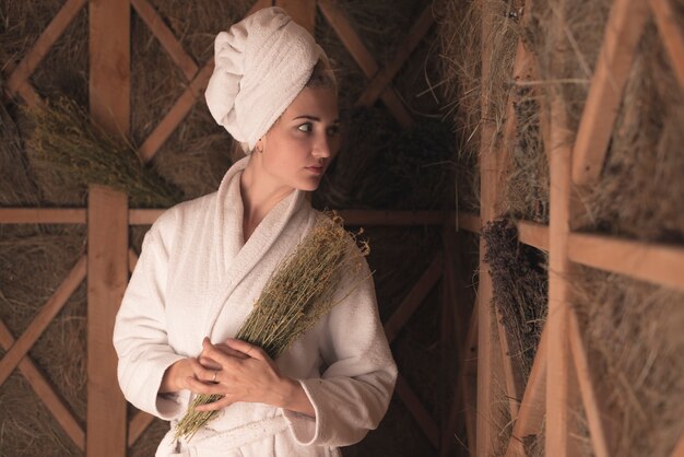 Young woman in bathrobe holding medical herbs